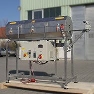 Transition Oven made of stainless steel with a switch box underneath and a hinged upper part for heating an endless steel belt